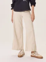 Pantalón ancho color beige claro, con corte holgado y costuras visibles en el frente de cada pierna.