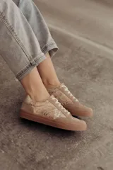 Zapatillas bajas color beige con estampado de piel de serpiente metalizada, cordones blancos y suela color caramelo.