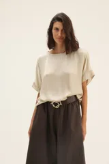 Blusa color beige de raso con ribete de lurex y mangas cortas.