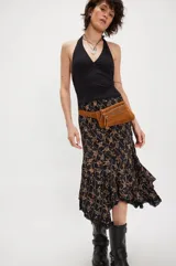 Falda midi negra con estampado floral en tonos marrones, corte al bies, ruedo asimétrico con encaje y cintura alta.