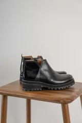 Botines negros de cuero con elástico lateral, detalle charol en el talón y suela track.