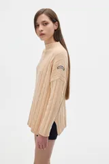 Sweater tejido color borgoña con cuello alto, corte oversize y mangas largas con detalle de trenzas verticales.