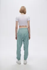 Pantalón de jogging color celeste con cintura elástica ajustable con cordón y puños elásticos. Presenta tres tiras verticales blancas en la parte inferior de la pierna.