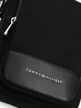 Bandolera Tommy Hilfiger negra con correa ajustable, cierre de cremallera, bolsillo interior con cremallera, bolsillo exterior con cremallera y logo metálico en la parte delantera.