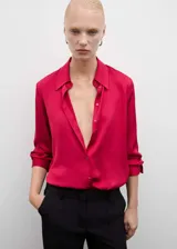 Camisa fucsia de tejido fluido con acabado satinado, cuello clásico, manga larga con puños abotonados y cierre frontal con botones.
