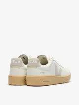 Zapatillas urbanas Veja V-90 color blanco hueso con logo lateral en gris y suela color caramelo.