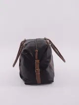 Bolso de viaje negro con detalles en cuero marrón, doble asa de mano y cierre superior con cremallera.