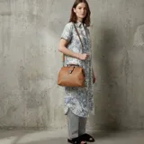 Cartera tipo doctor bag color marrón, con correa larga al hombro y cierre metálico.