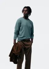 Buzo de tejido liso, color verde azulado, con cuello redondo y manga larga.