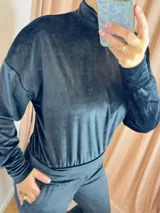 Conjunto deportivo negro de terciopelo, compuesto por un buzo de cuello alto con mangas largas y puños ajustados, y un pantalón jogger con cintura elástica.