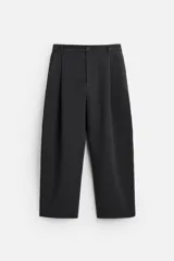 Pantalón negro de corte amplio con pliegues en la parte delantera, bolsillos laterales y traseros de ojal.