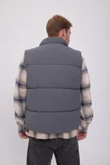 Chaleco puffer gris sin mangas con cuello alto y cierre de cremallera.