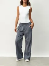 Pantalón deportivo color borgoña, de corte ancho y cintura elástica. Presenta una franja blanca vertical a lo largo de la pierna.