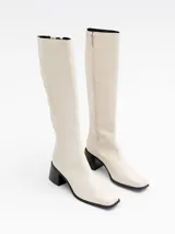 Bota alta color hueso, con caña recta, punta cuadrada y taco bloque negro.