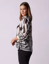 Blusa de gasa estampada marca Figueroa & Flower, color blanco con estampado abstracto en negro. Tiene cuello a la base con escote en V, apertura central con botones y mangas largas ¾ amplias.