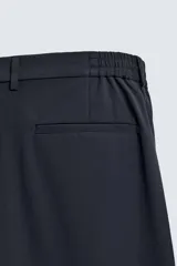 Pantalón regular fit color azul marino, confeccionado en tejido elástico. Cuenta con bolsillos frontales, bolsillos traseros de vivo con botón y cierre frontal con cremallera y botón.