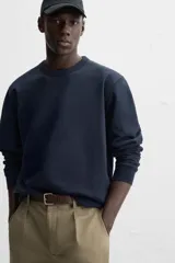Sudadera negra de corte holgado, cuello redondo y mangas largas con puños acanalados.