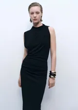 Vestido largo negro de tejido elástico con cuello drapeado y abertura lateral.