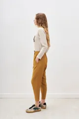 Pantalón de tiro medio color mostaza, de calce holgado que se ajusta al tobillo. Tiene cintura elastizada con tiras regulables.