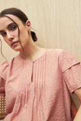 Blusa blanca de tela liviana con mangas cortas con volados y botón de nácar.
