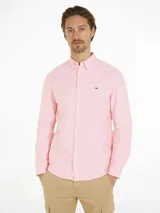 Camisa Tommy Jeans de corte regular, color rosa, confeccionada en algodón Oxford. Tiene cuello abotonado, manga larga y logo de la marca bordado en el pecho.
