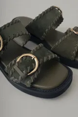 Sandalias de plataforma color verde militar, confeccionadas en cuero, con doble tira ancha con hebillas doradas y suela de goma negra.