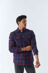 Sobrecamisa de algodón para hombre con interior de corderito, estampado a cuadros en tonos negro, blanco y azul. Tiene cierre de botones, bolsillos tipo cartera y logo en goma. El modelo usa talle M.