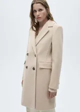 Abrigo de paño color beige, con cuello de solapa, doble botonadura y bolsillos con solapa.