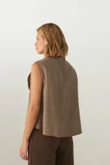 Chaleco marrón con solapas amplias y terminaciones envivadas. Diseño reversible y sin mangas.