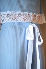 Pijama gris con textura acanalada, compuesto por una remera de manga larga con detalle de puntilla blanca en el ruedo y un pantalón recto con elástico en la cintura y detalle de puntilla blanca en los laterales.