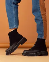 Botas cortas de cuero negro con cierre frontal con cremallera, suela track y costuras blancas.