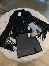 Minifalda negra ajustada con abertura lateral y strass plateados.