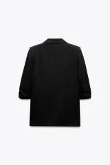 Blazer blanco con cuello solapa y hombreras. Manga por debajo del codo acabada en vuelta con trabilla y botón dorado. Bolsillos delanteros con solapa.