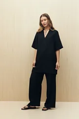 Vestido corto negro de línea relajada con cuello tipo solapa y escote en V profundo, mangas cortas amplias y calce suelto.