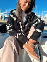 Camperón tejido oversize con capucha, bolsillos y estampa de ciervo.