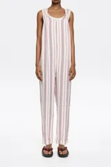 Mono largo de lino color crudo con rayas verticales rojas y azules. Tiene corte recto, escote redondeado pronunciado, tirantes anchos con trabillas para fruncir y espalda nadadora.