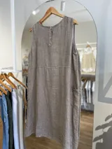 Vestido corto color beige de lino, con cuello redondo, sin mangas y bolsillos laterales.