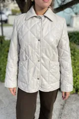Campera de cuero negra con diseño matelassé de rombos, cuello camisero, cierre frontal con botones a presión, dos bolsillos delanteros y puños con botón.