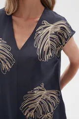 Remera de manga corta color azul marino con estampado de hojas de palmera en color beige y cuello en V.