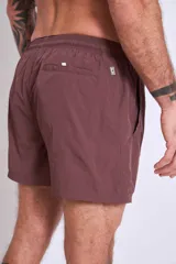 Short de baño color marrón con cordón ajustable en la cintura y logo estampado en blanco en la pierna izquierda.