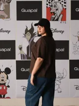 Remera marrón de manga corta y corte holgado, con estampado frontal de Mickey Mouse usando gafas de sol sobre un fondo de líneas onduladas y el texto "ALWAYS ON VACAY".