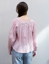 Blusa rosa claro de algodón con escote cuadrado, manga larga y bordado floral en el frente y las mangas.