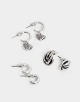 Set de tres pares de aros plateados: un par de argollas pequeñas, un par de argollas con dije de corazón rayado y un par de aros tipo botón con diseño ondulado.