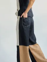 Pantalón ancho de corte recto con fit holgado, de lino color beige con bloques de color negro y marrón.