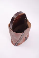 Bolso matero color bordó, de cuero, con doble asa (una de mano y otra larga desmontable), divisor interno para termo y mate, y bolsillo interior.