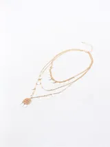 Collar dorado de tres hilos con dijes colgantes en forma de lágrima y un dije central con diseño calado.