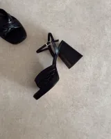 Sandalia de cuero vacuno color dorado, con plataforma y taco cuadrado. Presenta una tira delgada en el tobillo y detalle de nudo en la capellada.