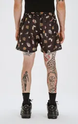 Short de baño negro con estampado de estilo tatuaje old school, que incluye diseños de rosas, sirenas, tiburones, anclas y diamantes. Cuenta con cintura elástica, cordón ajustable y cuatro bolsillos.