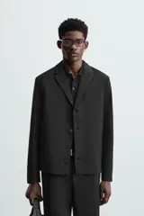 Blazer negro de corte regular, con cuello de solapas de muesca, manga larga con puños abotonados, bolsillos laterales ocultos en la costura de la cadera, bolsillo interior y cierre frontal con botonadura.