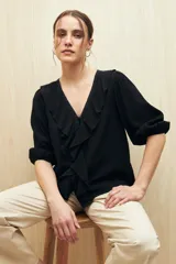 Blusa negra con mangas 3/4 y escote en V con volados.
